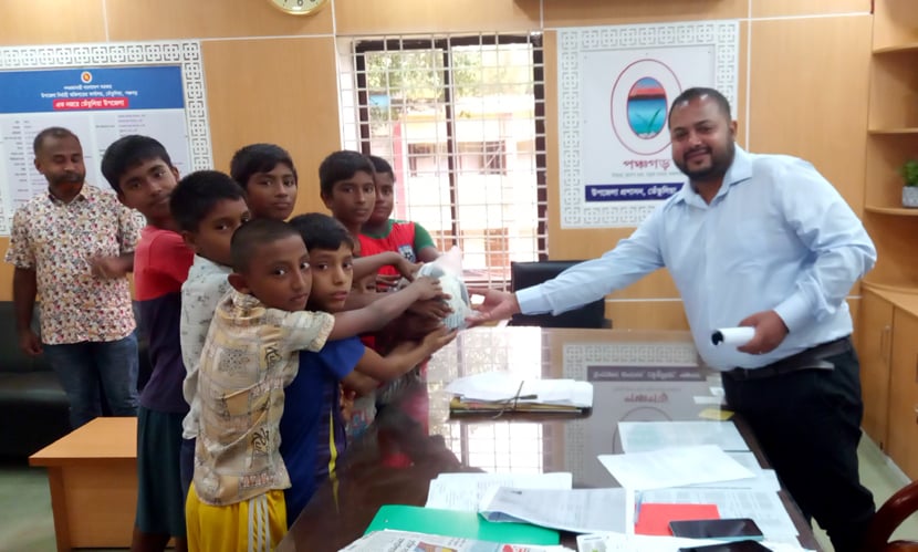 তেঁতুলিয়ার উপজেলা নির্বাহী কর্মকর্তার (ইউএনও) কাছ থেকে ফুটবল উপহার নিচ্ছে শিশুরা। ছবি: সংগৃহীত